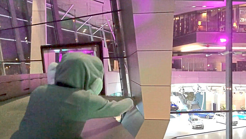 Die Gestalt im Hasenkostüm wirft Eier gegen die Glasfront der BMW-Welt.