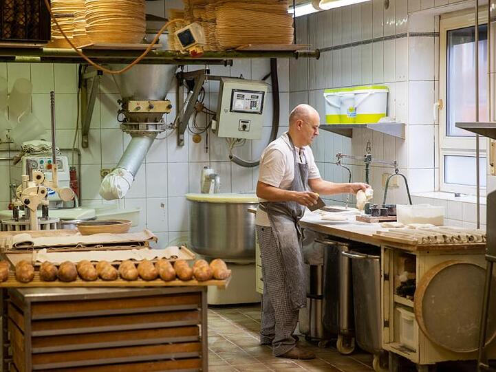 Arnd Erbel, Bäcker- und Konditormeister und Inhaber der Familienbäckerei, steht beim Teigabweigen in der Backstube. Foto: Daniel Karmann