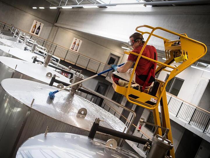 Ein Brauergeselle reinigt im Sudhaus der Brauerei die Lagertanks. Foto: Matthias Balk/Archivbild