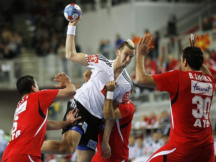 Pascal Hens (m) im Sprungwurf gegen die Spieler Tej (l) und Majed Amor Ben.