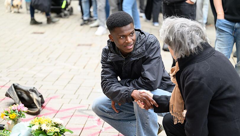 Suraj Mailitafi (l) von der Initiative "Gerechtigkeit für Lorenz" spricht mit einer Passantin an dem Ort, an dem der 21-Jährige von der Polizei erschossen wurde.