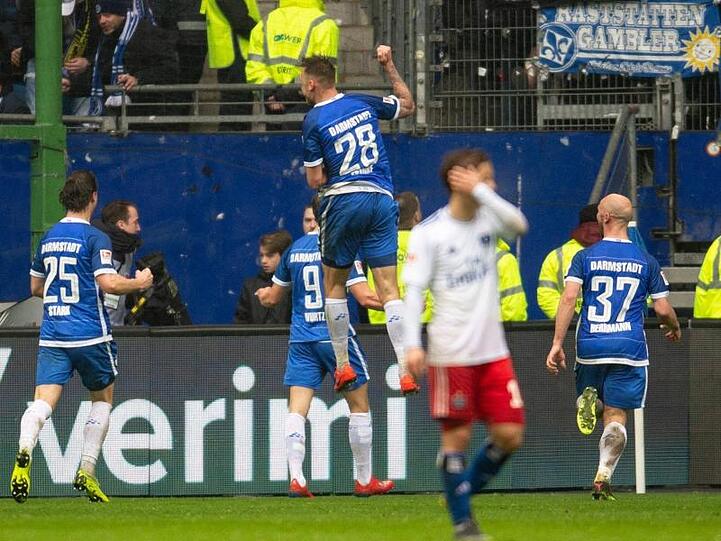 Während die Spieler von Darmstadt 98 den Treffer zum 3:2 in Hamburg feiern lässt ein HSV-Spieler den Kopf hängen.