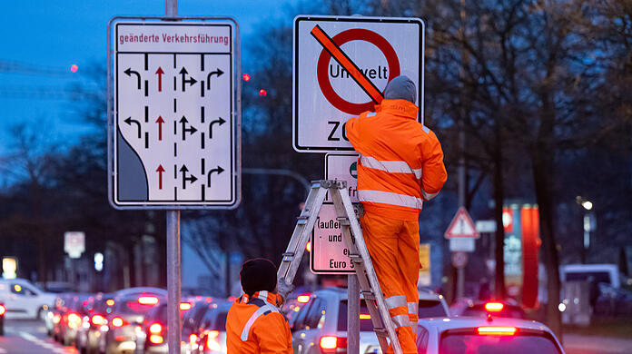 Den orangenen Klebestreifen auf dem Schild haben die zwei Arbeiter am Mittwoch entfernt. Denn ab jetzt gilt in der Innenstadt und dem Mittleren Ring ein Verbot von Euro-4-Dieseln.