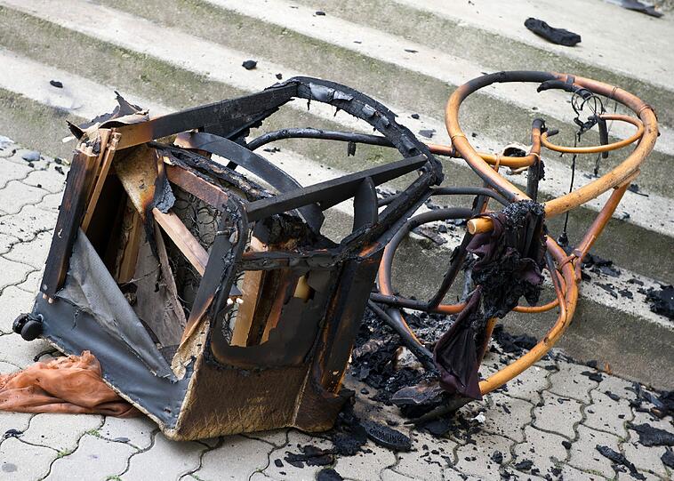 Ein verbrannter Sessel und ein Schaukelstuhl liegen am Samstag vor dem Treppenaufgang eines Plattenbaus in Frankfurt (Oder).