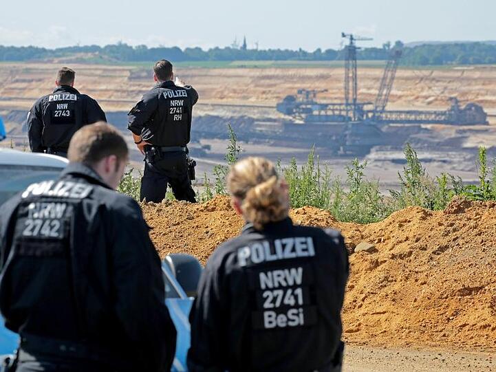 Einsatzwagen der Polizei haben sich am Aussichtspunkt Hochneukirch im Norden des Tagebaus Garzweiler gesammelt. Von dort hat man einen weiten Blick auf das riesige Abbaufeld.