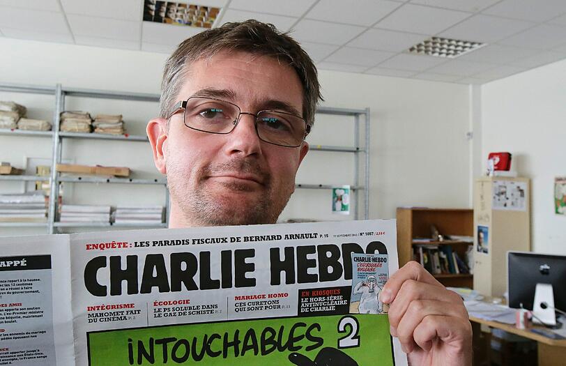Der Zeichner und Redakteur Charb gestern in seiner Redaktion, umringt von Kamerateams. Er steht jetzt unter Polizeischutz, wie die gesamte Redaktion.