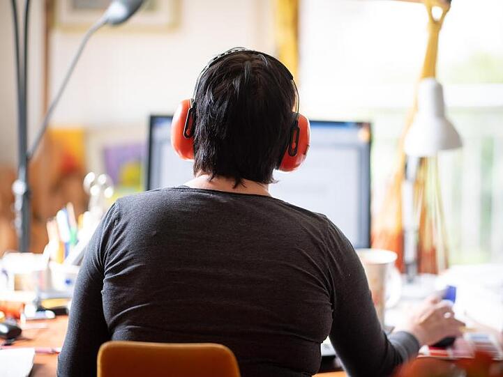 Eine Frau arbeitet mit Hörschutz im Homeoffice.