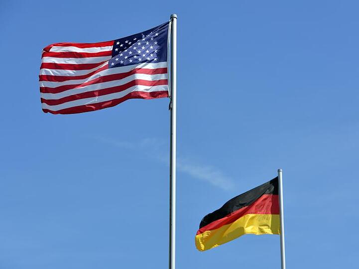 Die US-amerikanische und die deutsche Nationalflagge wehen vor dem Haupttor des US-Militärflughafens.