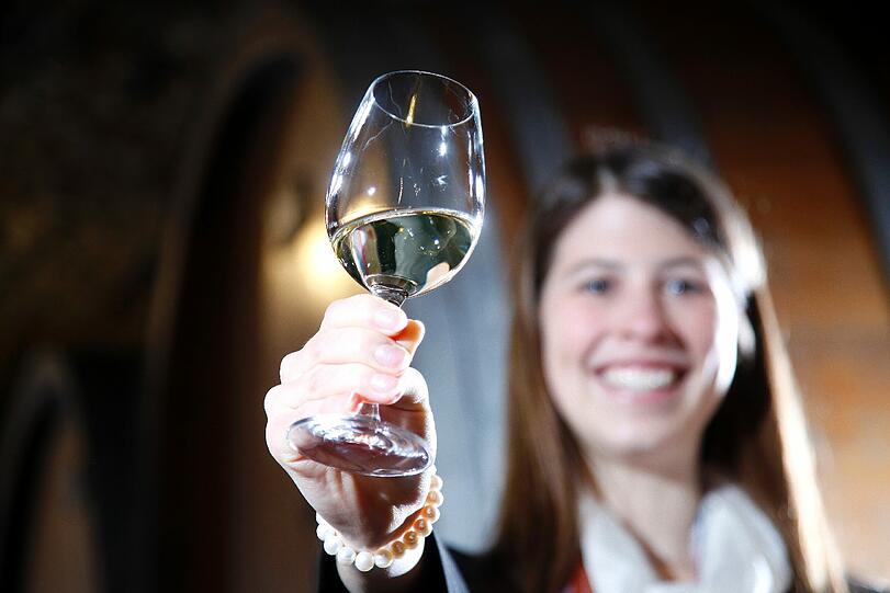 Die designierte fraenkische Weinkoenigin 2012/2013, Melanie Dietrich, posiert in Wuerzburg im Keller des Weinguts Buergerspital zum Heiligen Geist mit einem Glas Wein zwischen Faessern