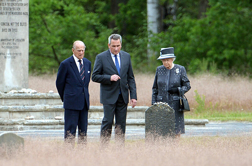 Königin Elizabeth II. und Prinz Philip stehen neben Jens-Christian Wagner (M), Direktor der Gedenkstätte, in der KZ-Gedenkstätte Bergen-Belsen (Niedersachsen)