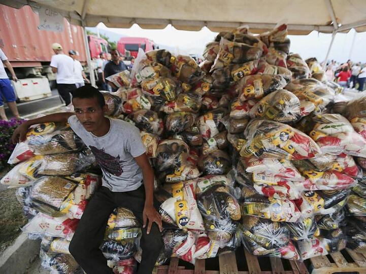 Ein Helfer sitzt neben Tüten mit Lebensmitteln, die von der venezolanischen Regierung im Grenzort Urena an Bedürftige verteilt werden.
