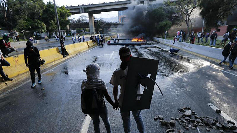 Sich gegenseitig Mut machen: Ein Pärchen hält während eines Protests gegen den sozialistischen Präsidenten Maduro auf einer Autobahn die Hände.