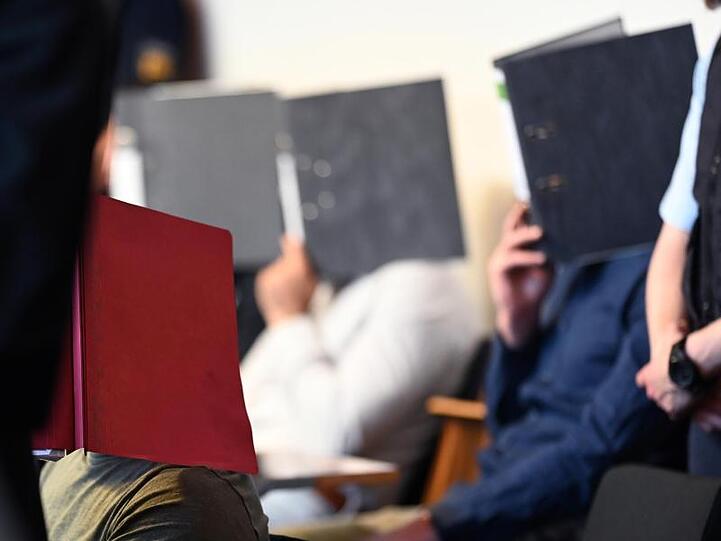 Angeklagte sitzen vor dem Prozessbeginn im Gerichtssaal im Landgericht in Freiburg.