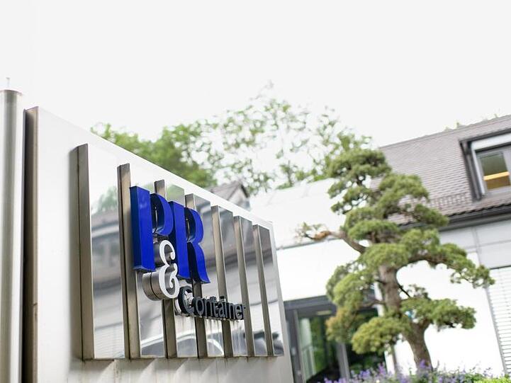 Das Logo von P&R Container vor einem Gebäude. Foto: Matthias Balk/Archiv