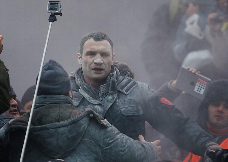 Vitali Klitschko versucht, bei Massenprotesten am Sonntag in Kiew die aufgebrachte Menge zu beruhigen. Dabei kam es zu Ausschreitungen.
