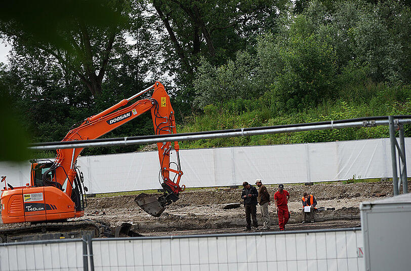 Dieser Bagger werkelt auf sensiblem Gelände: Ein Gitterzaun mit weißer Plane schirmt die archäologischen Grabungen nach Überresten des KZ-Außenlagers Dachau-Allach vor den Blicken Neugieriger ab. Die aufwendige Flächengrabung wird klären, ob hier ein Massengrab ist.