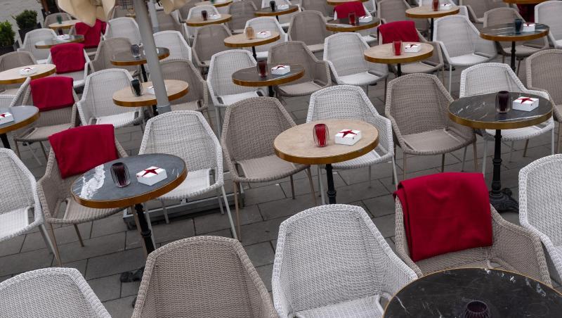 Zahlreiche leere Stühle vor einem Straßencafé. Foto: Peter Kneffel/dpa/Symbolbild