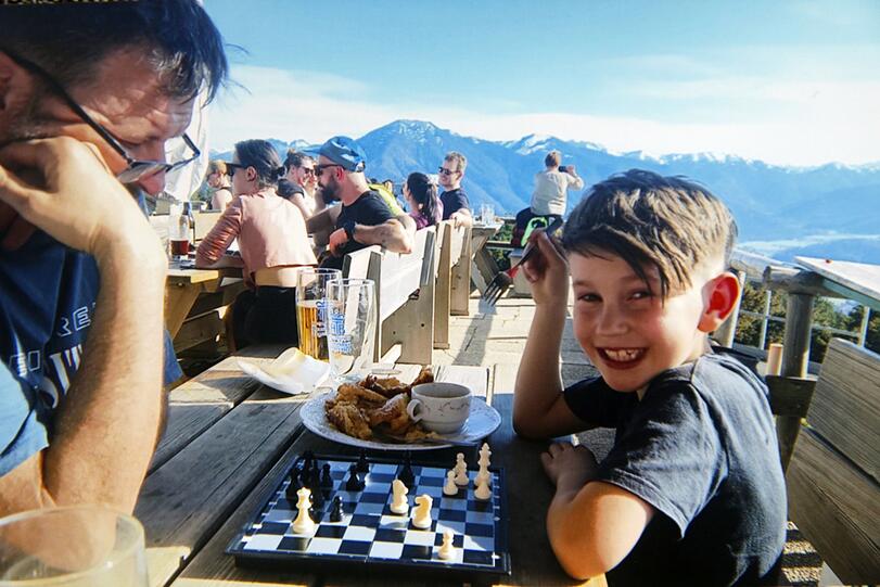 Das klappbare kleine Schachbrett muss bei Moritz Benischke (7) seit zwei Jahren immer dabei sein. Auch hier beim Wandern im Juni auf dem Wallberg, da spielt er in der Pause auf der Alm gegen Christian, einen Freund der Familie.