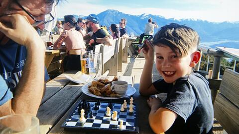 Das klappbare kleine Schachbrett muss bei Moritz Benischke (7) seit zwei Jahren immer dabei sein. Auch hier beim Wandern im Juni auf dem Wallberg, da spielt er in der Pause auf der Alm gegen Christian, einen Freund der Familie.