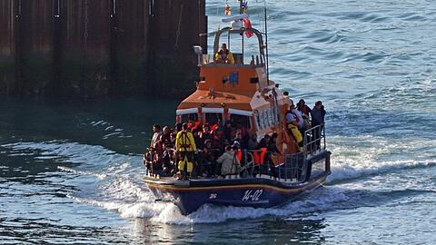 Eine Gruppe von Menschen wird mit einem kleinen Boot im Ärmelkanal an Bord eines Rettungsbootes nach Dover in Kent gebracht. Im Ärmelkanal haben britische Seenotretter mehrere Menschen, bei denen es sich vermutlich um Migranten handelt, aus dem Wasser gerettet. Das Thema Migration beschäftigt auch den Kanzler.