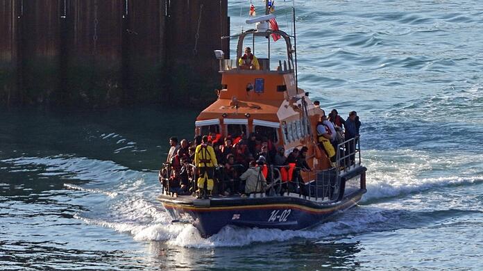 Eine Gruppe von Menschen wird mit einem kleinen Boot im Ärmelkanal an Bord eines Rettungsbootes nach Dover in Kent gebracht. Im Ärmelkanal haben britische Seenotretter mehrere Menschen, bei denen es sich vermutlich um Migranten handelt, aus dem Wasser gerettet. Das Thema Migration beschäftigt auch den Kanzler.