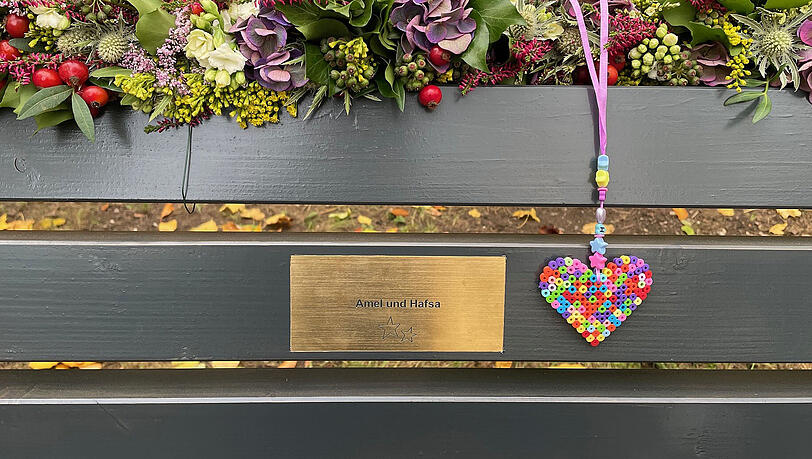 Die Bank am Flaucher mit einer Gedenktafel für Amel und Hafsa, die nach dem Anschlag auf die Verdi-Demo im Februar 2025 ihren Verletzungen erlagen. Die Bank am Flaucher mit einer Gedenktafel für Amel und Hafsa, die nach dem Anschlag auf die Verdi-Demo im Februar 2025 ihren Verletzungen erlagen.