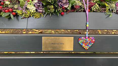Die Bank am Flaucher mit einer Gedenktafel für Amel und Hafsa, die nach dem Anschlag auf die Verdi-Demo im Februar 2025 ihren Verletzungen erlagen.