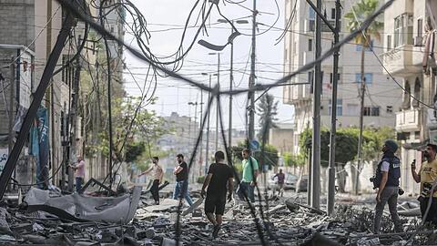 Palästinenser inspizieren das Umfeld des schwer beschädigten Al-Jawhara-Turm, nachdem der Turm von israelischen Luftangriffen getroffen worden war.