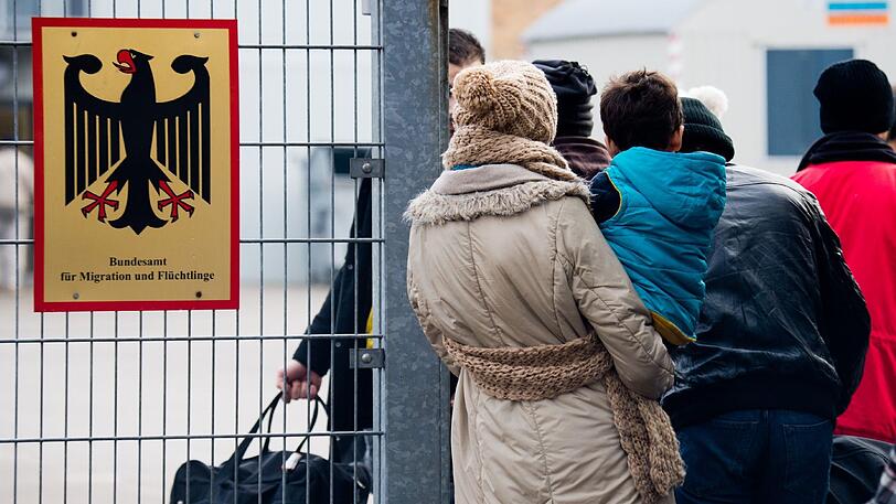 Flüchtlinge stehen 2015 neben einem Schild vom "Bundesamt für Migration und Flüchtlinge" an der Landesaufnahmebehörde Niedersachsen in Braunschweig (Niedersachsen). Das Thema Zuwanderung soll am 26. Oktober bei den Jamaika-Verhandlungen zur Sprache kommen.