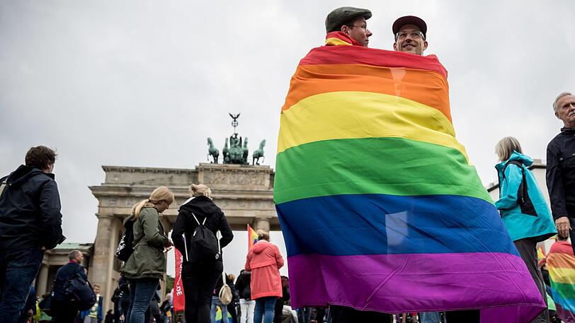 Marcel J. aus Dresden (l) und Henri V. aus Berlin stehen, gehüllt in eine Regenbogenflagge, am 30.06.2017 bei einer Veranstaltung der SPD zur Ehe für alle vor dem Brandenburger Tor in Berlin.