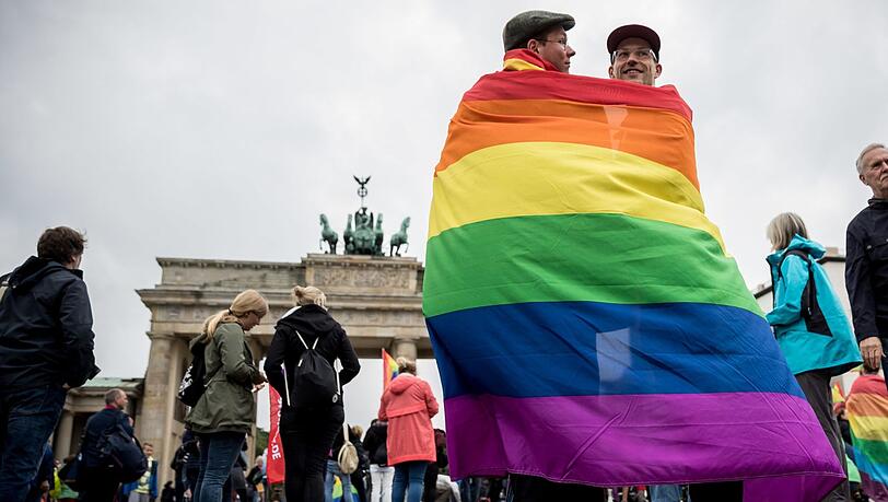Marcel J. aus Dresden (l) und Henri V. aus Berlin stehen, gehüllt in eine Regenbogenflagge, am 30.06.2017 bei einer Veranstaltung der SPD zur Ehe für alle vor dem Brandenburger Tor in Berlin.
