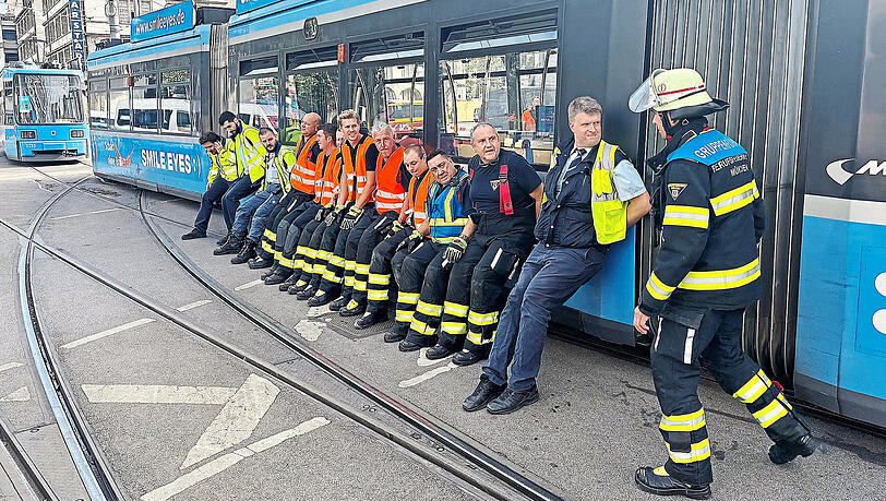 Mit vereinten Kräften schieben die Einsatzkräfte die Straßenbahn wieder zurück aufs Gleis.  Einsatzfotos Berufsfeuerwehr München