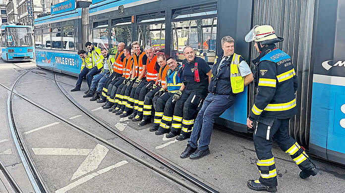 Mit vereinten Kräften schieben die Einsatzkräfte die Straßenbahn wieder zurück aufs Gleis.  Einsatzfotos Berufsfeuerwehr München