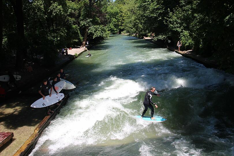 Im Sommer geht&rsquo;s kurzärmlig aufs Board: Eisbachsurfer erfrischen sich hinterm Haus der Kunst.