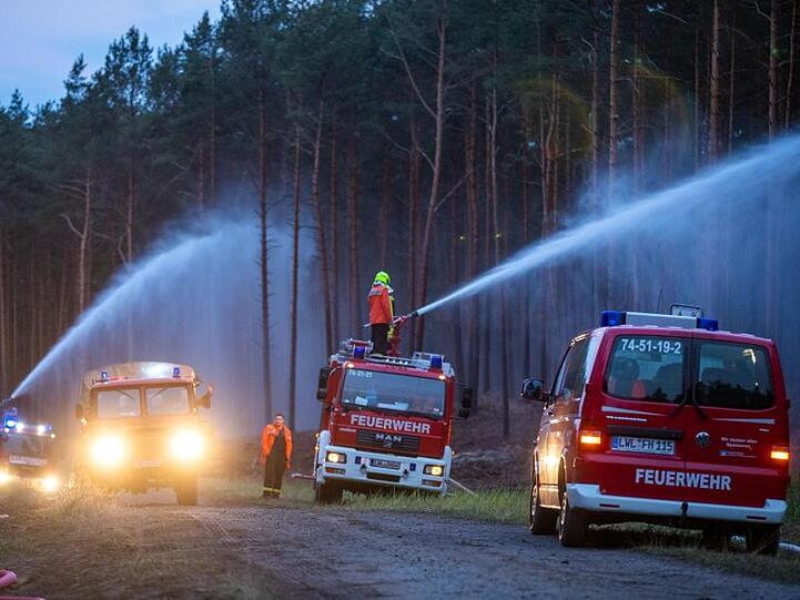 Feuerwehrleute löschen in der Nähe der evakuierten Ortschaft Alt Jabel einen großflächigen Waldbrand.