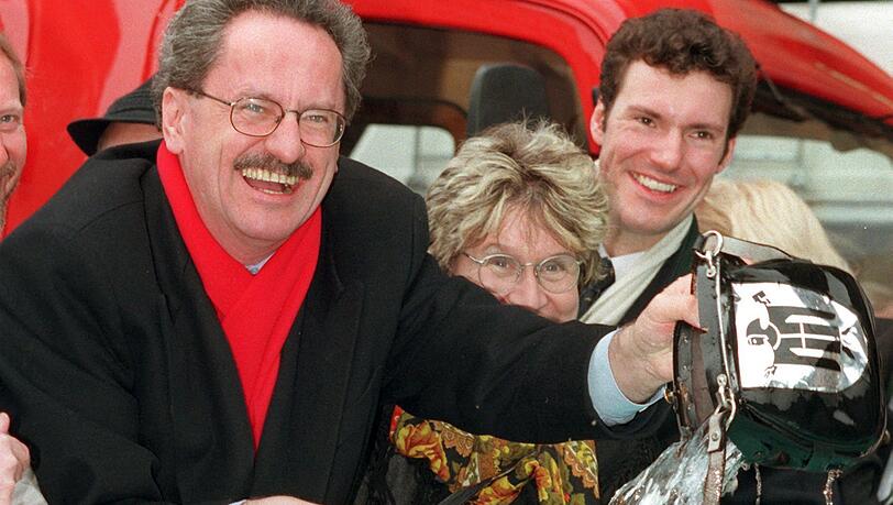 Noch ohne Werbung am Brunnenrand: Münchens Oberbürgermeister Christian Ude (SPD, l) wäscht am Mittwoch (25.2.1998) im Beisein von Bürgermeisterin Gertraud Burkert und Faschingsprinz Florian Drasch (r) im Fischbrunnen am Münchner Marienplatz den Geldbeutel der Stadt. (Archiv)