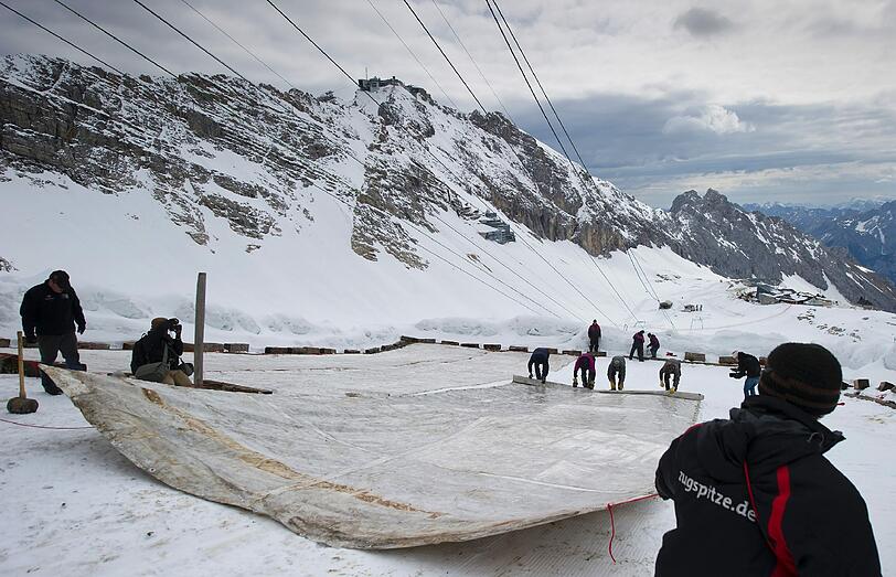Arbeiter decken auf dem Zugspitzplatt bei Grainau den Gletscher mit einer Plane ab, um ein Abschmelzen zu verhindern. Deutschlands einziger Gletscher soll waehrend der warmen Sommermonate mit der 500 bis 600 Quadratmeter grossen Plane vor Sonne und Regen geschuetzt werden.