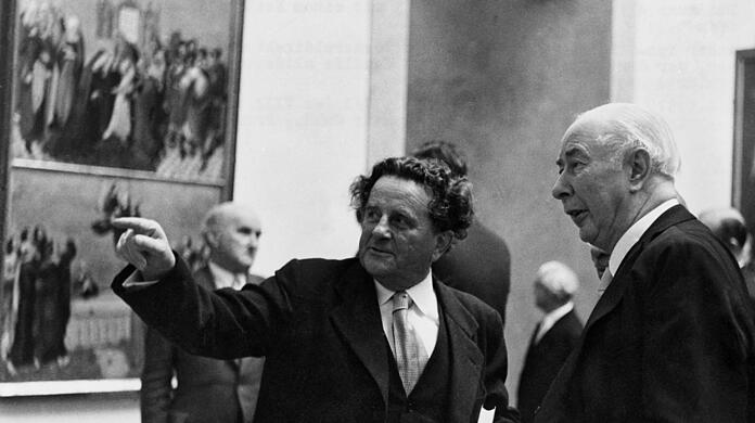 Bei der Wiedereröffnung der Alten Pinakothek 1957 zeigt der vier Jahre zuvor wieder eingesetzte Generaldirektor Ernst Buchner dem Bundespräsidenten und großen Kunstfreund Theodor Heuss die Höhepunkte der Sammlung. Buchner, ab Mai 1933 NSDAP-Mitglied, war von März 1933 bis 1945 verantwortlich für die Pinakotheken.