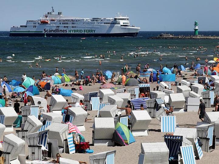 Hochbetrieb am Ostseestrand von Warnemünde, während im Hintergrund die Scandlines-Fähre "Copenhagen" einläuft.