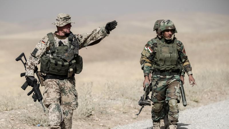 Bundeswehrsoldaten und kurdische Peshmerga Soldaten gehen in der Ausbildungseinrichtung Bnaslawa bei einer Übung am Rand einer Straße entlang. Nun prüft die Bundesregierung den Teilrückzug der Soldaten aus Erbil. Bundeswehrsoldaten und kurdische Peshmerga Soldaten gehen in der Ausbildungseinrichtung Bnaslawa bei einer Übung am Rand einer Straße entlang. Nun prüft die Bundesregierung den Teilrückzug der Soldaten aus Erbil.