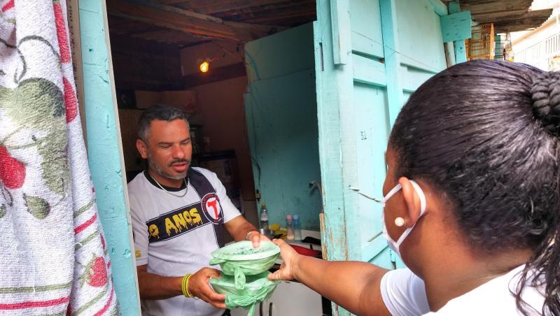 Laryssa da Silva reicht einem Mann zwei Essenspakete in die Wohnung. Sie ist eine von 700 "Straßenpräsidenten" in Paraisopolis. Laryssa da Silva reicht einem Mann zwei Essenspakete in die Wohnung. Sie ist eine von 700 "Straßenpräsidenten" in Paraisopolis.