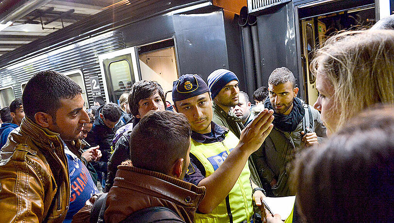 Flüchtlinge mit einem schwedischen Polizisten am Stockholmer Bahnhof. Das Land führt vorübergehend wieder Grenzkontrollen ein. Flüchtlinge mit einem schwedischen Polizisten am Stockholmer Bahnhof. Das Land führt vorübergehend wieder Grenzkontrollen ein.