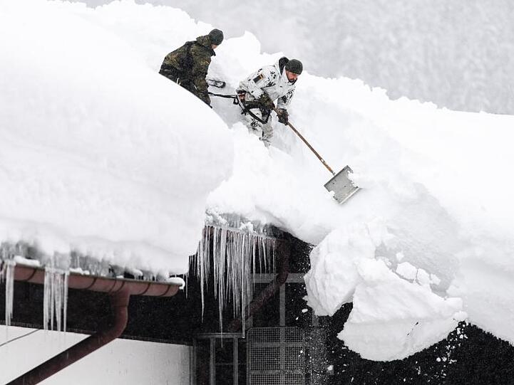 Einsatzkräfte der Bundeswehr befreien das Dach eines Wohnhauses von Schneemassen.