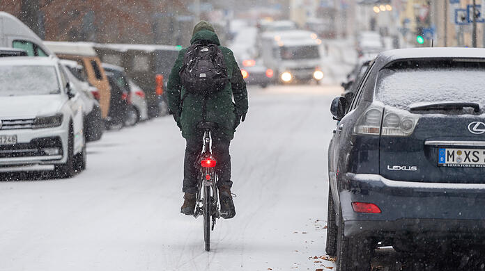 Ein Radler fährt über eine verschneite Straße in der Innenstadt.