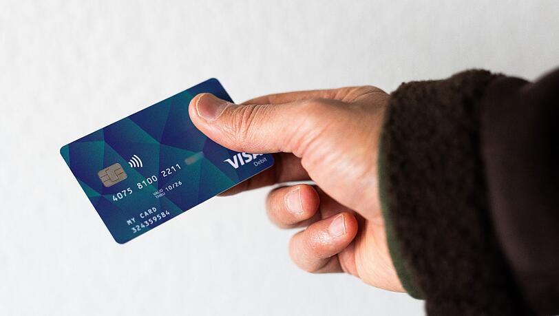 Ein Geflüchteter hält eine Debitkarte in der Hand.