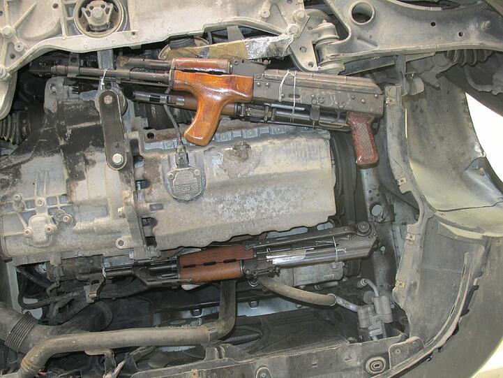 Motorblock: Nach Abbau der Spritzwasserabdeckungen kamen unter dem Motorblock des VW Golf mehrere Kalaschnikow-Gewehre zum Vorschein. Sie waren &bdquo;kunstvoll&ldquo; mit Draht an die Aggregathaltungen gebunden. Trotzdem wurden die Waffen entdeckt.