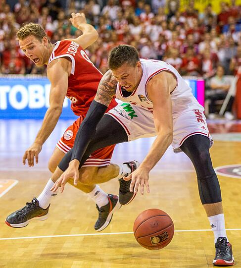 Heiko Schaffartzik (l) von München und Daniel Theis von Bamberg kämpfen um den Ball.