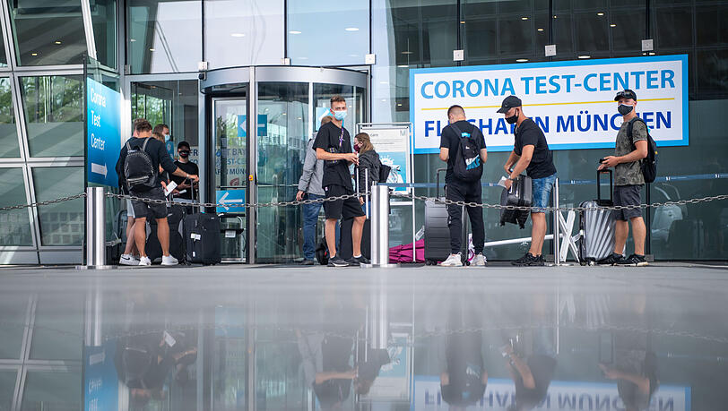 Wann sie wohl ihr Ergebnis erfahren? Junge Männer warten vor der Teststation am Münchner Flughafen.