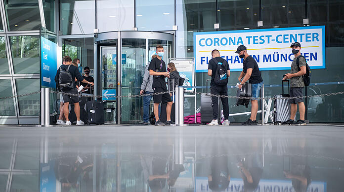 Wann sie wohl ihr Ergebnis erfahren? Junge Männer warten vor der Teststation am Münchner Flughafen.