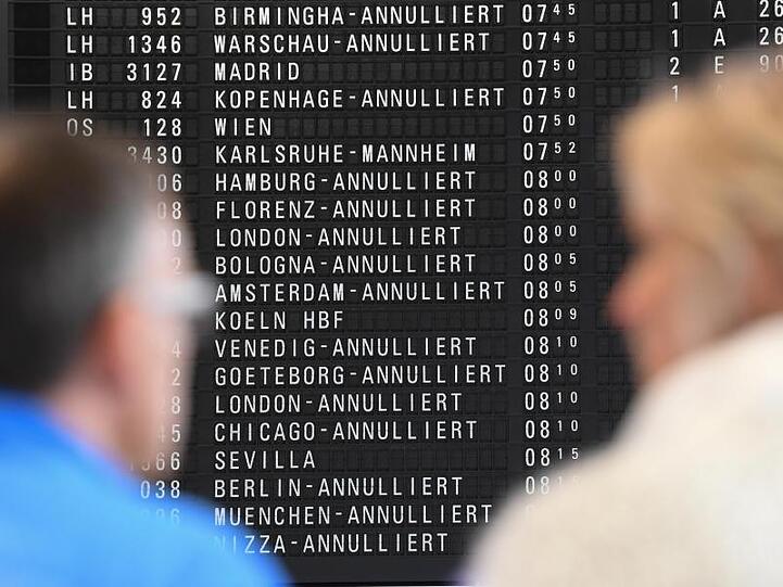 Fluggäste stehen im Terminal 1 des Frankfurter Flughafens vor einer Anzeigetafel, auf der annullierte Flüge angezeigt sind.